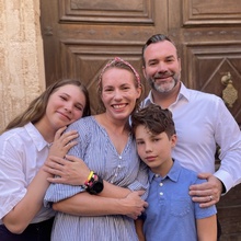 Alums Megan and Sean O'Connor pose with their two children outside a ornate wooden door.