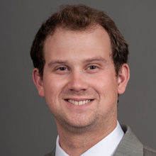 Austin Henderson, smiling against a grey backdrop.