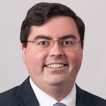 Alexander Lewis, smiling against a white backdrop