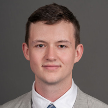 Justin Rempe, smiling against a grey backdrop.
