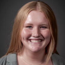 Abbie Boeding, smiling for a headshot against a dark gray backdrop.