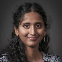 Nihitha Vallaru smiles for a professional photo against a dark backdrop.