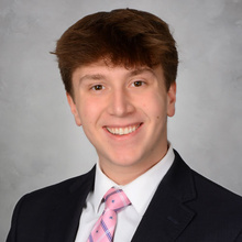 Quinn Cote posing for a professional headshot against a light gray backdrop.