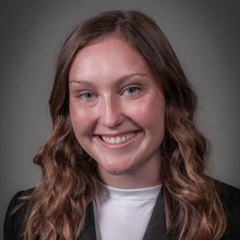 Dani Arkfeld smiles for a professional photo against a dark gray backdrop.