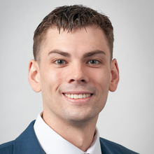 Luke Forszt smiles for a professional photo against a light gray backdrop.