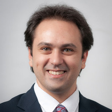 Adam Kahn smiles for a professional photo against a light gray backdrop.