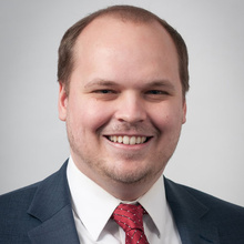 Ethan Miner smiles for a professional photo against a light gray backdrop.
