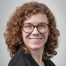 Ruth Olson smiles for a professional photo against a light gray backdrop.