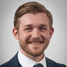 Samuel Reynoldson smiles for a professional photo against a light gray backdrop.