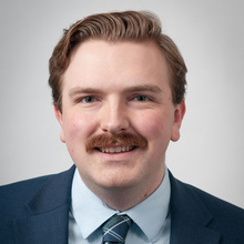 Caleb Slater smiles for a professional photo against a light gray backdrop.