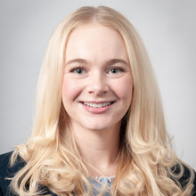 Brooke Timmerman smiles for a professional photo against a light gray backdrop.