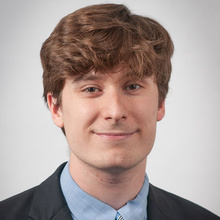 August Warren smiles for a professional photo against a light gray backdrop.