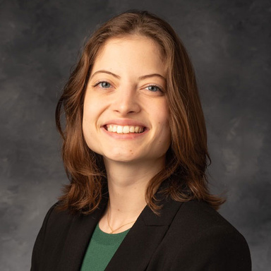 Siduri Beckman smiles for a photo in a dark green shirt and black blazer.