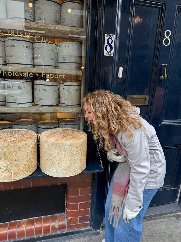 student pretending to take a bite of Neal's Yard Cheese in London