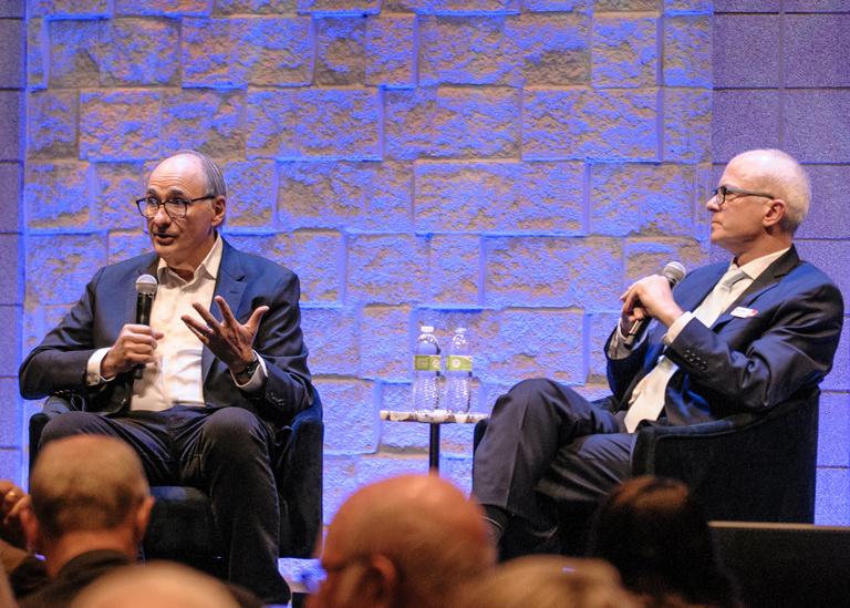 David Axelrod and Ben Kieffer speak on a stage to a small group before the lecture.