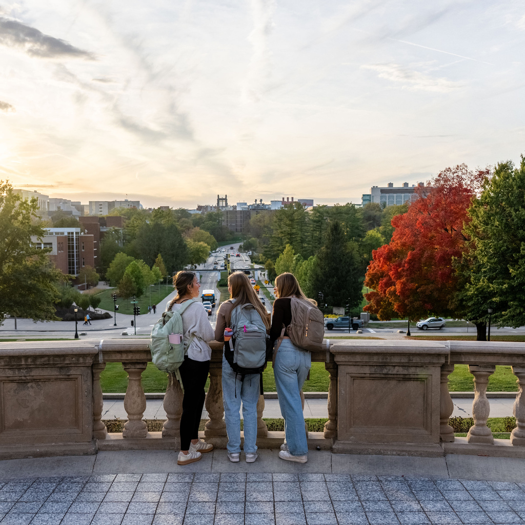 Three students standing on a balcony overlooking Iowa City