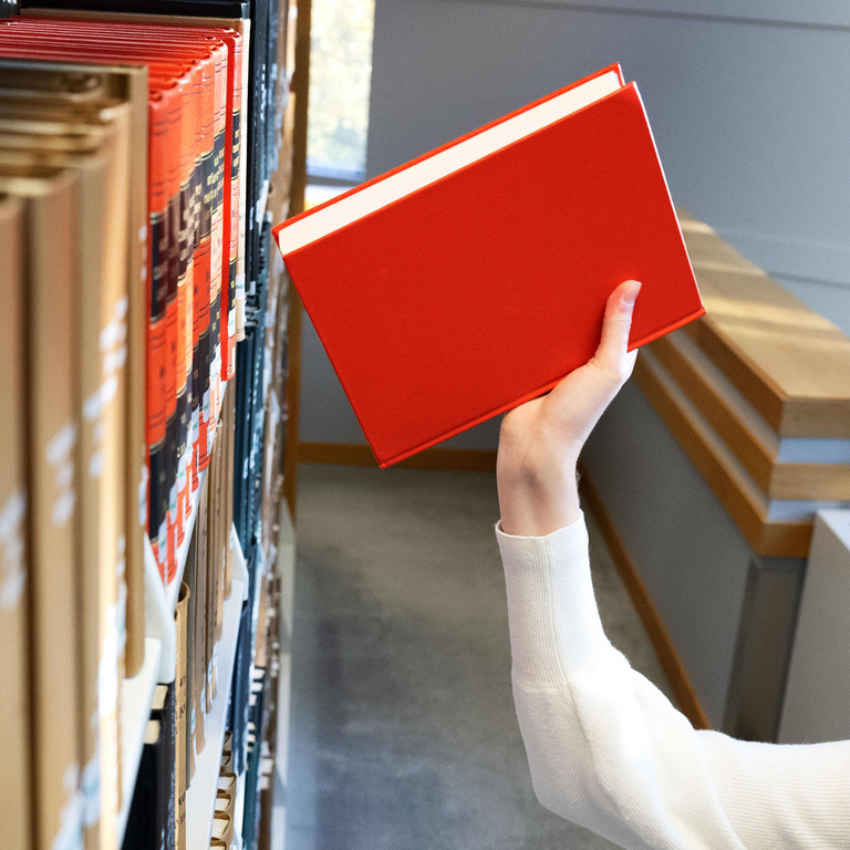 Someone placing a book on a bookshelf in the Law Library.