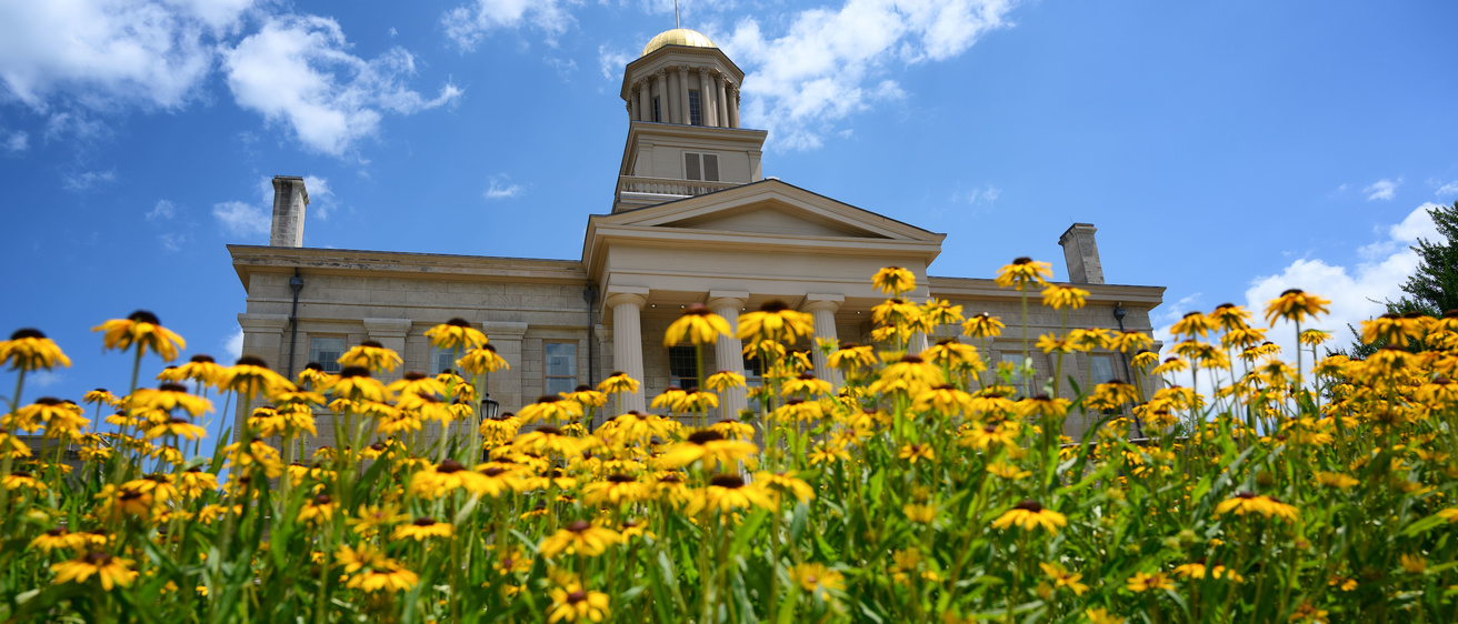 Iowa Campus in Summer in front of Old Capital with yellow flowers.