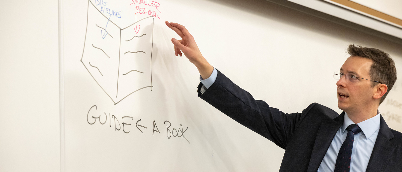 Professor Sean Sullivan teaching antitrust law, pointing in front of a white board. 