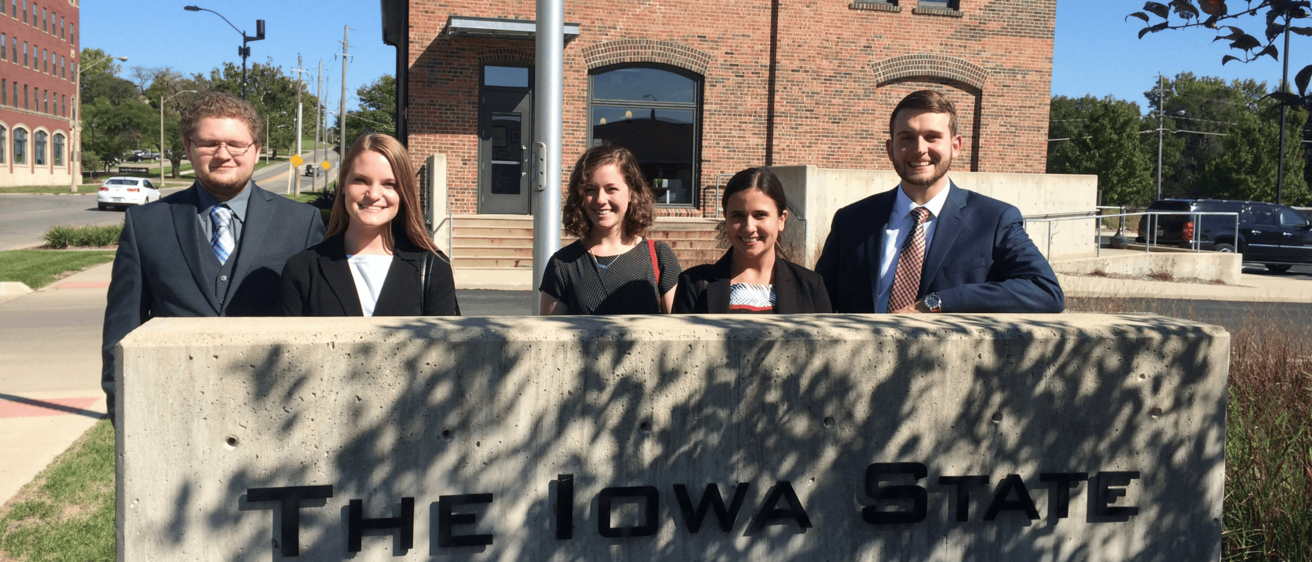 Students stand in front of the sign at the Iowa Bar Assciation.