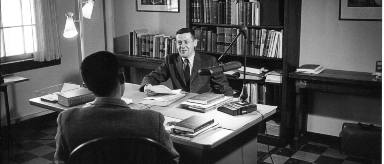 Sandy Boyd sitting at a desk in the 1950s in a black and white photo.