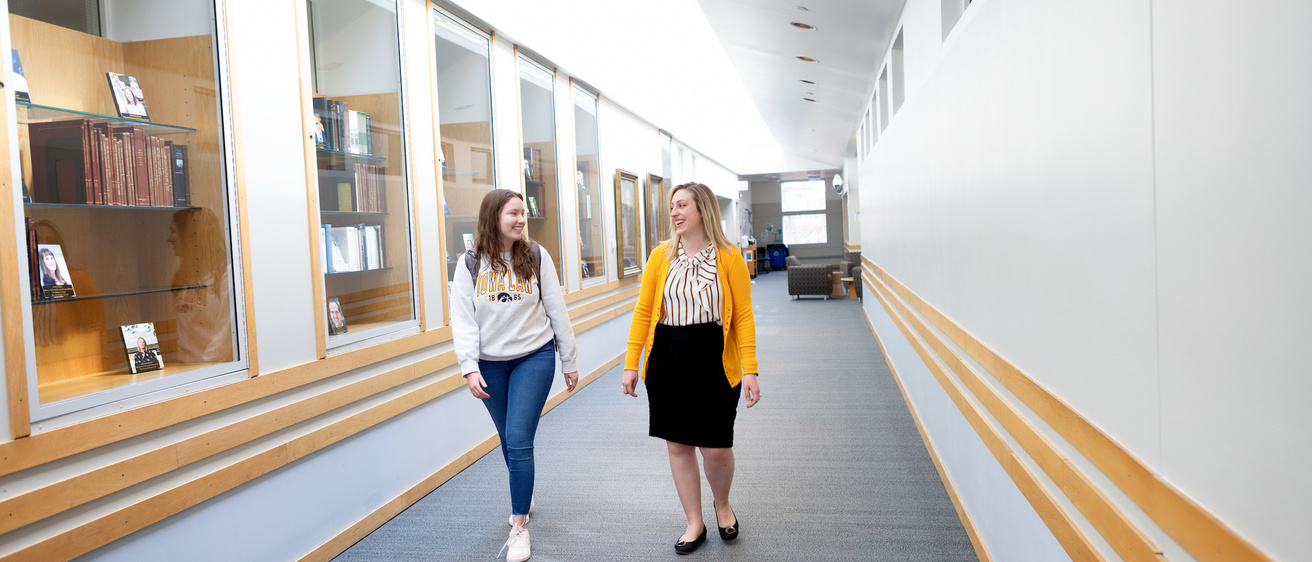 Melissa Norman, director of career services, walks down the hallway by the dean's suite with a current law student. 