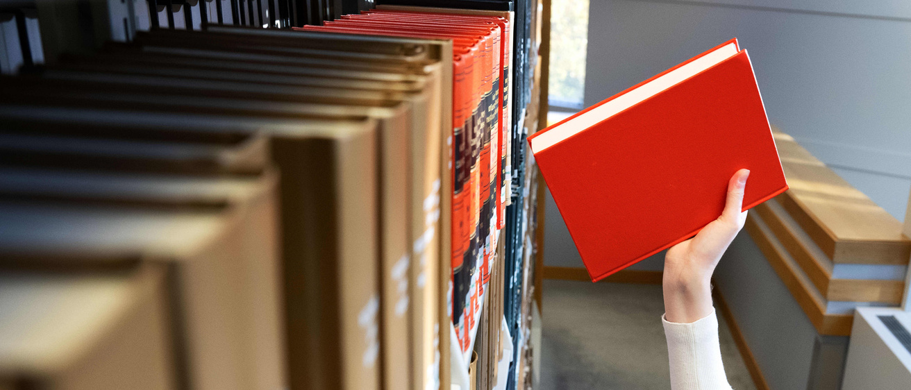 Someone placing a book on a bookshelf in the Law Library.