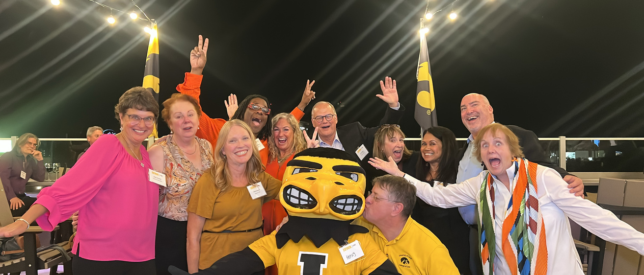 A group of alumni pose with Herky the Hawk