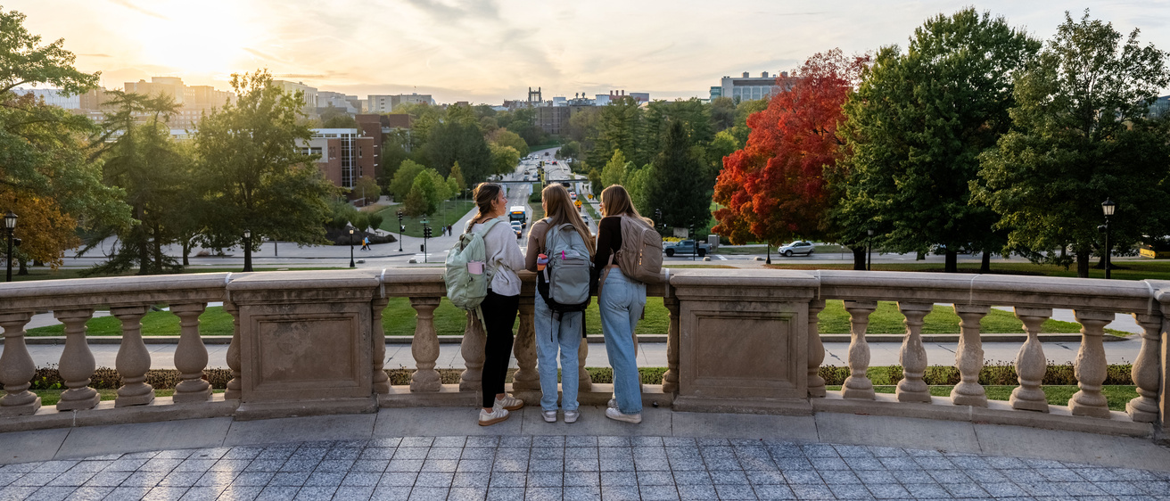 Three students standing on a balcony overlooking Iowa City