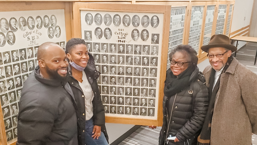 Iowa Law grad Abishi Cunningham's family standing next to the Class of 1941's composite photo