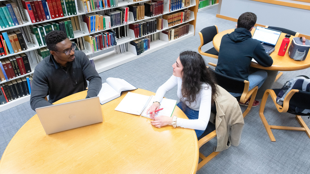 Two students study at a table in the library in the Boyd Law Building.