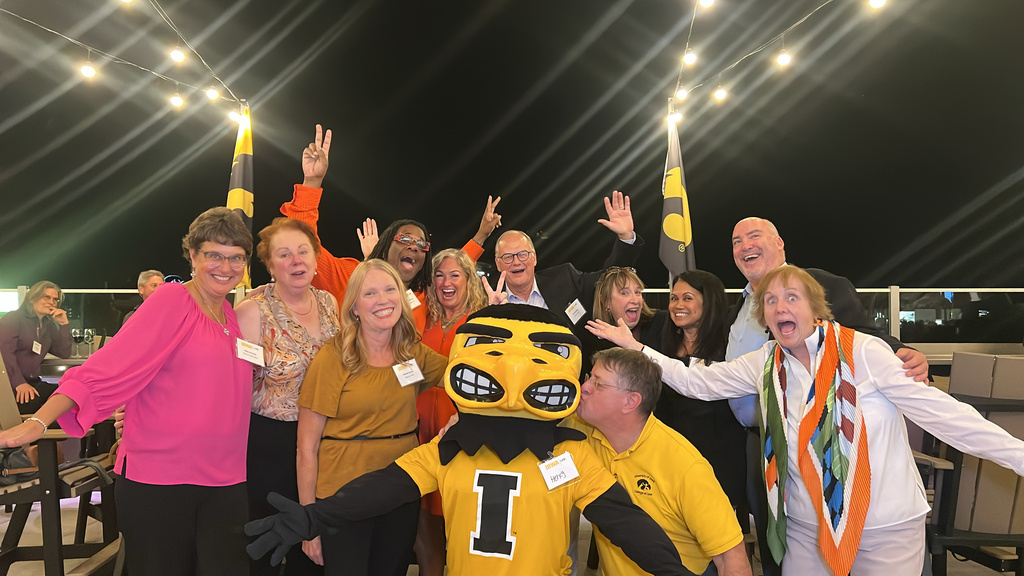 A group of alumni pose with Herky the Hawk